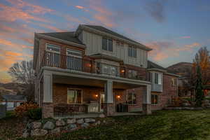 Back of house featuring a covered patio area, a mountain view, board and batten siding, and brick exterior