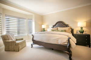 Carpeted bedroom featuring crown molding and baseboards