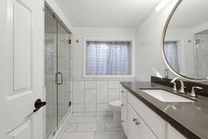 Full bathroom featuring vanity, a stall shower, and tile walls