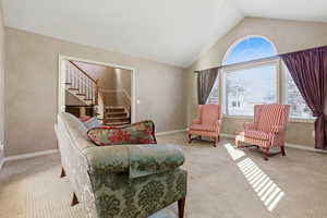 Sitting room featuring lofted ceiling, stairway, and carpet flooring
