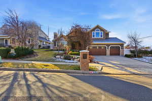 View of front of home with  large concrete driveway, beautiful landscaping , an attached 3 car garage, stone siding, and stucco siding