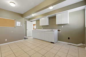 Huge washroom featuring cabinet space, hookup for a washing machine, and light tile patterned flooring