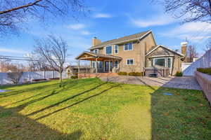 Spacious back of property with a fenced backyard, stucco siding, a chimney, a hot tub, and a patio area