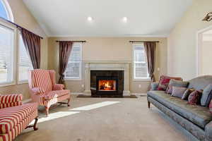 Living area with lofted ceiling, a premium gas fireplace, and carpet floors