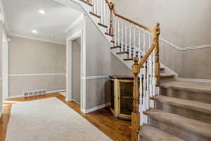 Stairway featuring wood finished floors, crown molding, and recessed lighting