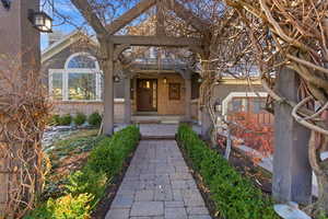 Entrance to property with covered porch,  brick siding and stunning floral trellis