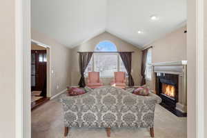 Living area with a fireplace with beautiful  hearth, lofted ceiling, and carpet
