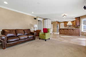 Living room with recessed lighting, light carpet, crown molding, and light tile patterned floors