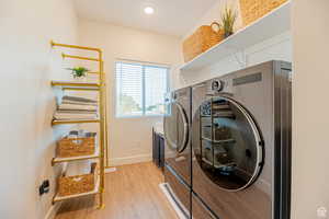 Laundry area featuring light wood-type flooring and washing machine and dryer