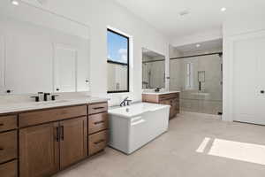 Full bathroom with a stall shower, a soaking tub, two vanities, recessed lighting, and light tile patterned flooring