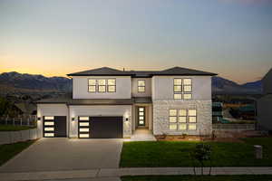 View of front of property with stone siding, stucco siding, driveway, and a mountain view