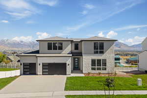 View of front of property featuring a mountain view, stucco siding, driveway, stone siding, and an attached garage