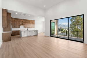 Unfurnished living room with a mountain view, light wood-type flooring, recessed lighting, and a high ceiling