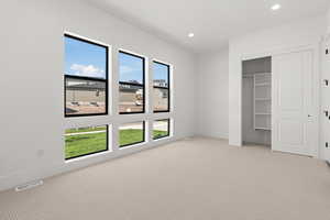 Unfurnished bedroom featuring light carpet, a closet, and recessed lighting