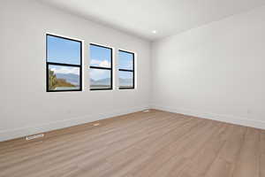 Empty room with light wood finished floors, a mountain view, and recessed lighting