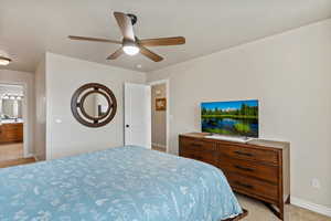 Bedroom featuring ensuite bathroom, a ceiling fan, light colored carpet, and a textured ceiling