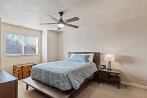 Bedroom featuring light carpet, ceiling fan, and a textured ceiling