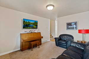 Living area featuring carpet, a textured ceiling, and stairs