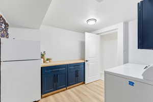 Laundry area featuring cabinet space, light wood finished floors, and independent washer and dryer