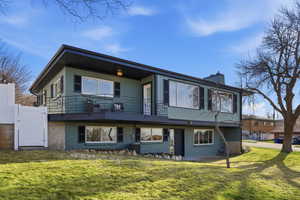 Back of property featuring a gate, a balcony, a yard, and a chimney