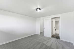 Unfurnished bedroom featuring dark colored carpet and baseboards