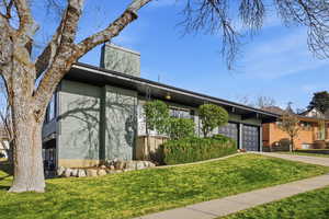 Mid-century home featuring brick siding, a front yard, concrete driveway, and a garage