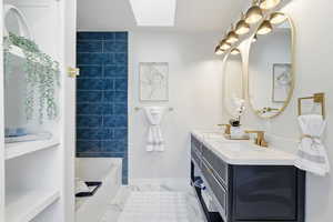 Full bath with a skylight, double vanity, and tub / shower combination