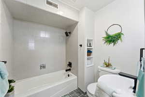Full bath with bathing tub / shower combination and dark tile patterned flooring
