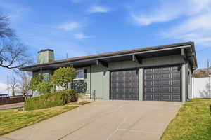 View of front of home with a chimney, driveway, and an attached garage