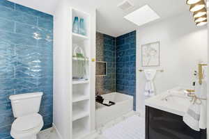 Full bath with double vanity, bathtub / shower combination, a skylight, and tile walls