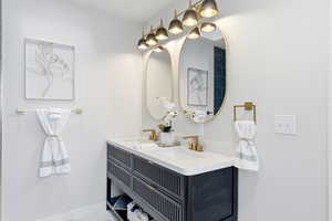 Full bathroom with double vanity and baseboards