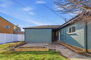 Rear view of property featuring a patio, a shingled roof, and a vegetable garden