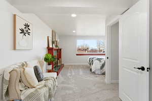 Living area featuring light colored carpet, a fireplace with raised hearth, and recessed lighting