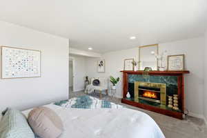 Bedroom featuring carpet flooring, a high end fireplace, and recessed lighting