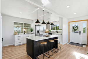Kitchen featuring a kitchen breakfast bar, hanging light fixtures, white cabinetry, a kitchen island, and backsplash