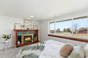 Carpeted bedroom with a high end fireplace and recessed lighting