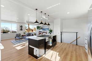 Kitchen featuring appliances with stainless steel finishes, decorative light fixtures, light stone counters, light wood finished floors, and recessed lighting