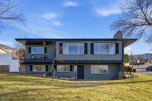 Back of house featuring a balcony, brick siding, a chimney, and a gate