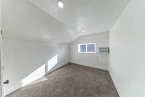 Bonus room with a textured ceiling, vaulted ceiling, carpet floors, recessed lighting, and a wall unit AC