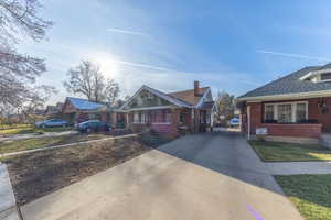 View of front facade with a residential view, driveway, brick siding, and roof with shingles