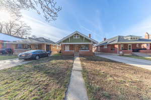 Bungalow-style home featuring brick siding, covered porch, and driveway