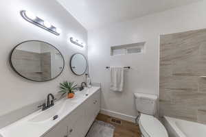 Bathroom featuring double vanity, dark wood-type flooring, and shower / bathtub combination