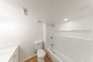Bathroom with vanity, shower / bath combination, a textured ceiling, and light wood-style floors