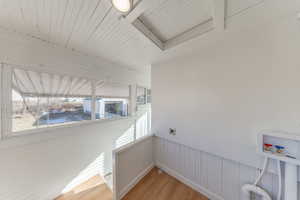 Washroom featuring a wainscoted wall, wood walls, light wood-style flooring, wood ceiling, and hookup for a washing machine
