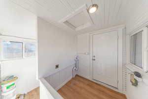 Laundry area with wooden ceiling, light wood-type flooring, wood walls, hookup for an electric dryer, and wainscoting