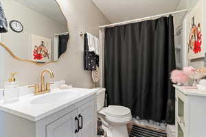 Bathroom featuring curtained shower, a textured wall, a textured ceiling, and vanity
