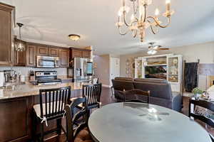 Dining room with a chandelier, ceiling fan, and dark wood finished floors