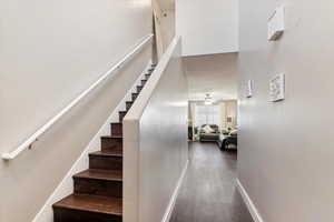 Stairway with wood finished floors and a ceiling fan