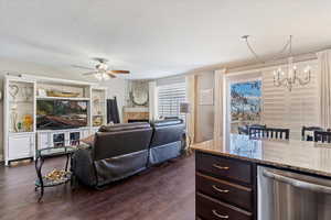 Living room featuring dark wood-style floors, a tiled fireplace, and a chandelier