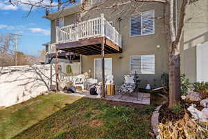Back of property with stucco siding, a patio area, and a wooden deck